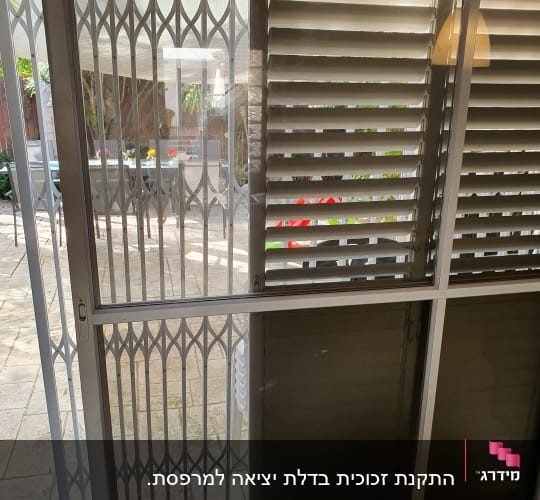 חלון זכוכית עם סורגים ותריסים פתוחים למחצה